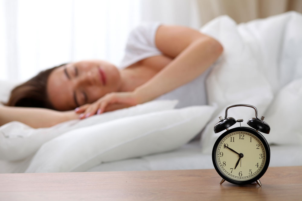 Woman sleeping next to an alarm clock